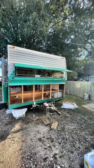 70's era RV being refurbished. Aluminium white and aqua camper with exposed wood frame.